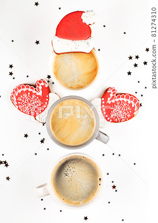 Three cups of coffee in shape of snowman with ginger cookie Santa hat and mittens. 81274310