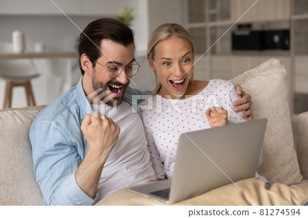 Happy excited millennial couple with digital device celebrating success Happy excited millennial couple with digital device celebrating success 81274594