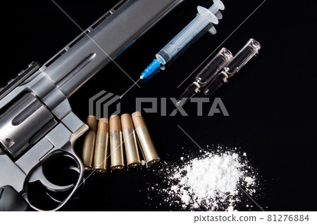 A syringe with an open needle lies on the table next to the drugs and the gun. A pistol with bullets, syringe and drugs lie on the black table. Sale, possession and distribution of drugs today A syringe with an open needle lies on the table next to the drugs and the gun. A pistol with bullets, syringe and drugs lie on the black table. Sale, possession and distribution of drugs today 81276884