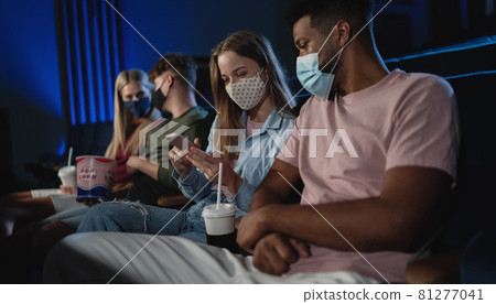 Cheerful young couple with smartphone in the cinema, coronavirus concept. Cheerful young couple with smartphone in the cinema, coronavirus concept. 81277041