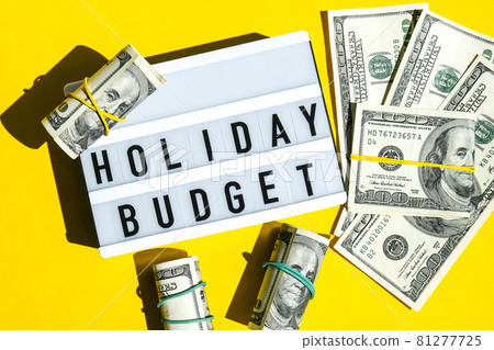 Lightbox board with word HOLIDAY BUDGET on yellow background around dollar banknotes. Money, Business, finance, investment, saving 81277725