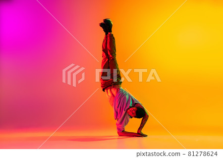 Caucasian man, break dancing dancer ptacticing in casual clothes isolated over gradient pink yellow background at dance hall in neon light. Caucasian man, break dancing dancer ptacticing in casual clothes isolated over gradient pink yellow background at dance hall in neon light. 81278624