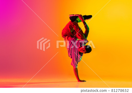 Full length portrait of young stylish man, break dancing dancer in casual clothes isolated over gradient pink yellow background at dance hall in neon light. Full length portrait of young stylish man, break dancing dancer in casual clothes isolated over gradient pink yellow background at dance hall in neon light. 81278632