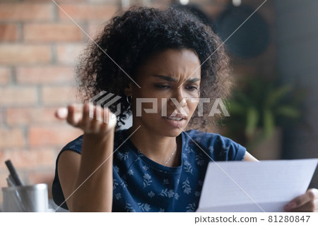 Frustrated millennial young Black woman reading paper letter 81280847