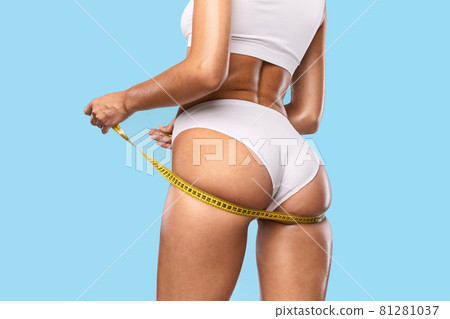 Closeup of Unrecognizable Lady Measuring Hip With Yellow Tape 81281037