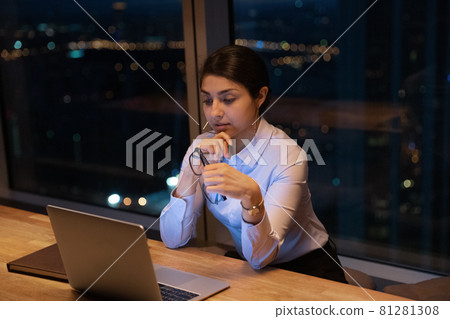 Indian businesslady looks at laptop reading e-mail thinks over information Indian businesslady looks at laptop reading e-mail thinks over information 81281308