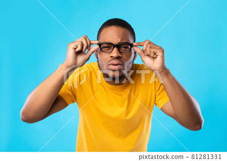 African American Guy With Poor Eyesight Squinting Eyes, Blue Background African American Guy With Poor Eyesight Squinting Eyes, Blue Background 81281331