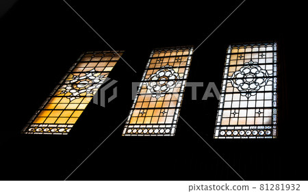 Simple patterned antique stained glass window silhouettes frame on black background in The national gallery. Simple patterned antique stained glass window silhouettes frame on black background in The national gallery. 81281932