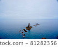 Rocks towering over the blue sea 81282356