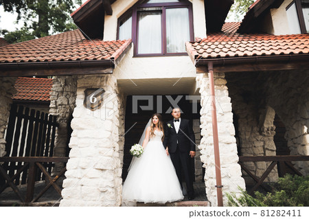 Newly married couple running and jumping in park while holding hands Newly married couple running and jumping in park while holding hands 81282411