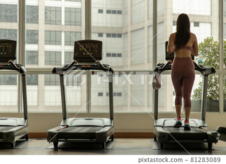 Back view of young woman on running track at gym or fitness club. 81283089