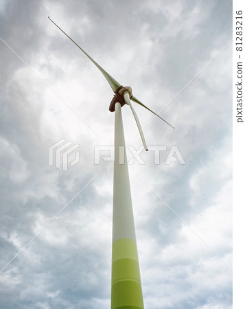 Wind turbines against cloudy sky in an open field 81283216