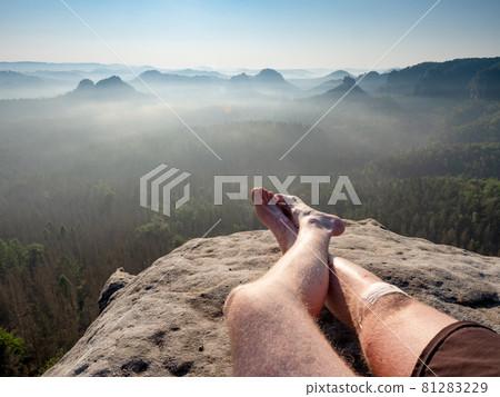 Resting man. Traveler\'s naked legs pointed towards to mountain peak 81283229
