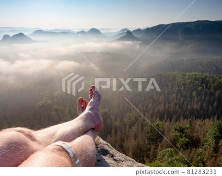 View above barefoot male body in black pants sleeping on cliff View above barefoot male body in black pants sleeping on cliff 81283231
