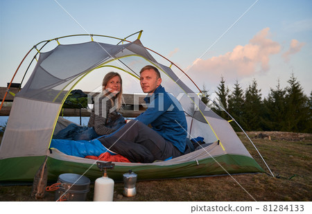 Man and woman just woken up in tent after sweet night in the open air, watching amazing view of the morning mountains. Concept of hiking, camping and relationships. 81284133