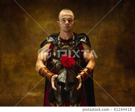 Close up of medieval person, brutal man, warrior or knight in war equipment isolated on vintage dark background. Comparison of eras, art, history, retro style concept 81284418