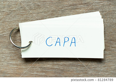 Flash card with handwriting word CAPA (abbreviation of corrective action and preventive action) on wood background 81284789