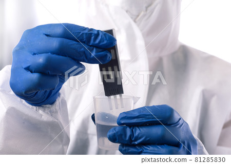 Checking the water quality. Scientist dip a test strip into a glass of water to determine the quality of the water Checking the water quality. Scientist dip a test strip into a glass of water to determine the quality of the water 81285830