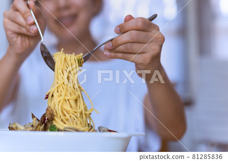 Woman eating tasty Italian spaghetti on white bowl with spoon and fork. Woman eating tasty Italian spaghetti on white bowl with spoon and fork. 81285836