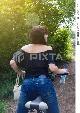 A brunette woman on a bicycle arches her back like a cat, a beautiful athletic figure 81286066