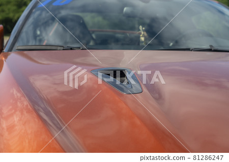 Air intake on the hood of an orange sports car. Air intake on the hood of an orange sports car. 81286247