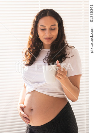 Happy pregnant young beautiful woman drinks tea during morning breakfast. Pregnancy and maternity leave. 81286341