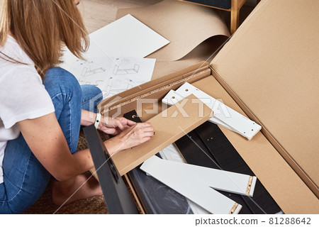 Woman reading manual instruction to assemble furniture 81288642