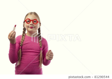 Sympathetic little caucasian girl paints her lips with red lipstick on a white background 81290544