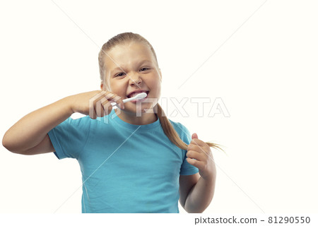 Cute cheerful caucasian little girl in a blue t-shirt brushes her teeth on a white background with a place for text Cute cheerful caucasian little girl in a blue t-shirt brushes her teeth on a white background with a place for text 81290550