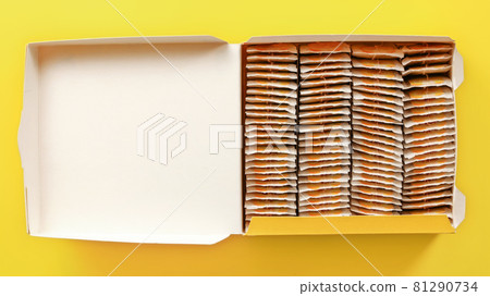 Top down view, box full of tea bags on yellow board. 81290734