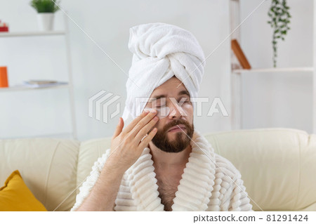 Bearded man applying eye patches on his face. Wrinkles and face home care for men. Bearded man applying eye patches on his face. Wrinkles and face home care for men. 81291424