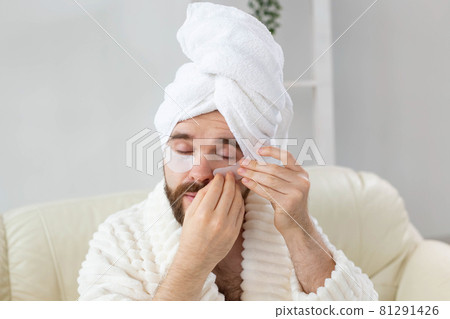 Bearded man applying eye patches on his face. Wrinkles and face home care for men. Bearded man applying eye patches on his face. Wrinkles and face home care for men. 81291426