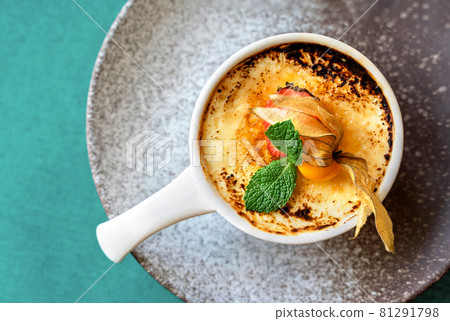 Delicious creme brulee dessert with caramelized cane sugar, fresh berries and mint leaves in white clay bowl on a grey and green background. Flat lay style. Mockup for cafe or restaurant with copy Delicious creme brulee dessert with caramelized cane sugar, fresh berries and mint leaves in white clay bowl on a grey and green background. Flat lay style. Mockup for cafe or restaurant with copy 81291798