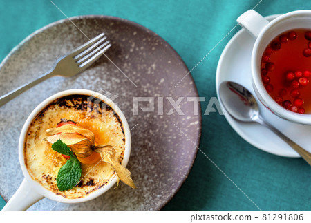 Delicious creme brulee dessert decorated with fresh berries and mint leaves and herbal tea with cranberries on a grey and green background. Flat lay style. Mockup for cafe or restaurant with copy Delicious creme brulee dessert decorated with fresh berries and mint leaves and herbal tea with cranberries on a grey and green background. Flat lay style. Mockup for cafe or restaurant with copy 81291806