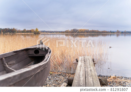 Old wooden boat on the shore of beautiful misty lake and autumn forest landscape. Autumn forest and lake background. Great design for any purposes. Old wooden boat on the shore of beautiful misty lake and autumn forest landscape. Autumn forest and lake background. Great design for any purposes. 81291807