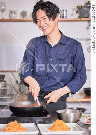 Young man in an apron cooking pasta, cooking boy image 81292541
