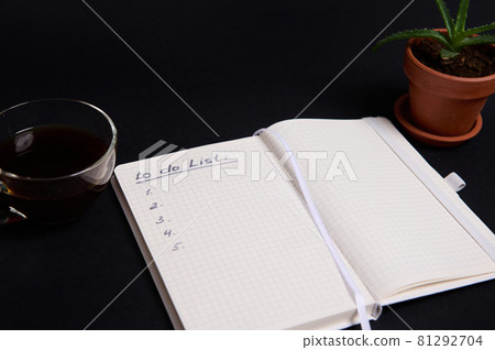 Opened notepad, organizer with list to do on blank white sheets, cup of coffee and potted succulent in clay pot, on black background with copy space. Business, Organization, Time Management concept. 81292704