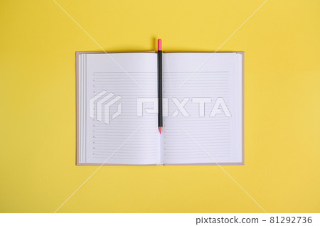 A color pencil in the middle of an open organizer with clean blank white sheets with copy space. Flat lay composition on yellow background 81292736