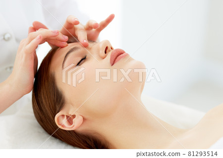 Therapist doing myofascial or buccal massage on face and head for female client lying at beauty center or spa salon Therapist doing myofascial or buccal massage on face and head for female client lying at beauty center or spa salon 81293514