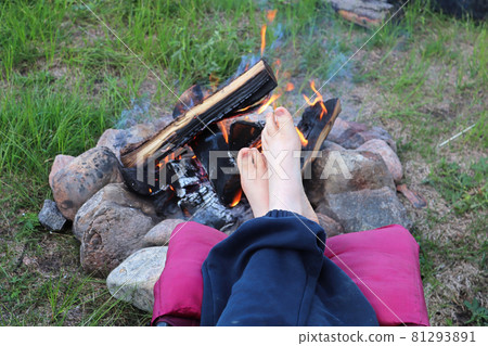 A young child puts its feet up to warm by the campfire A young child puts its feet up to warm by the campfire 81293891