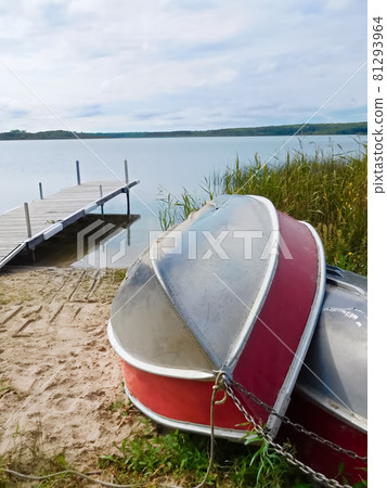 Two aluminum boats pulled up on shore with a dock in the background Two aluminum boats pulled up on shore with a dock in the background 81293964