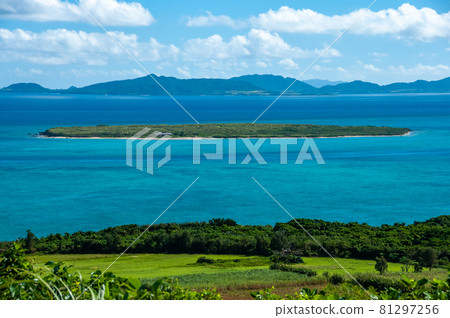 Breathtaking view of the island of Kayama surrounded by turquoise sea, between Ishigaki Island in the background and very green fields in the foreground. 81297256