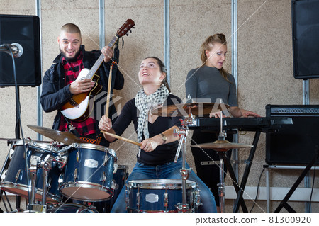 Music band with cheerful girl drummer rehearsing Music band with cheerful girl drummer rehearsing 81300920