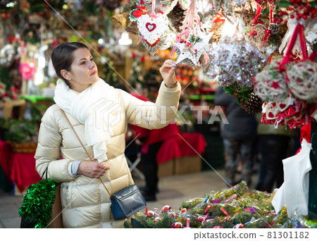 Lovely woman buying decorations for Xmas at an open air market Lovely woman buying decorations for Xmas at an open air market 81301182