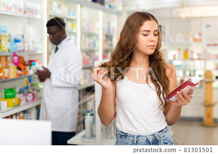 Young woman who came to the pharmacy chooses a hair care remedy Young woman who came to the pharmacy chooses a hair care remedy 81301501
