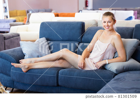 Woman buyer lying barefoot with pillow on the sofa in furniture shop Woman buyer lying barefoot with pillow on the sofa in furniture shop 81301509
