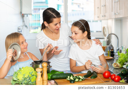 Young woman and two daughters cooking together Young woman and two daughters cooking together 81301653