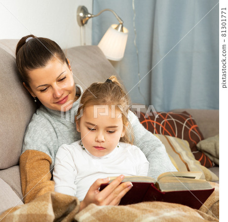 Mother reads an interesting book for her small daughter 81301771