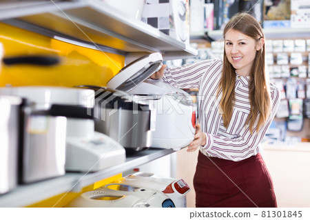 Saleswoman offering multicooker in household appliances shop 81301845