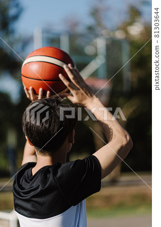 Sports and recreation concept a young male teenager practicing shooting a basketball separately in the court after school Sports and recreation concept a young male teenager practicing shooting a basketball separately in the court after school 81303644